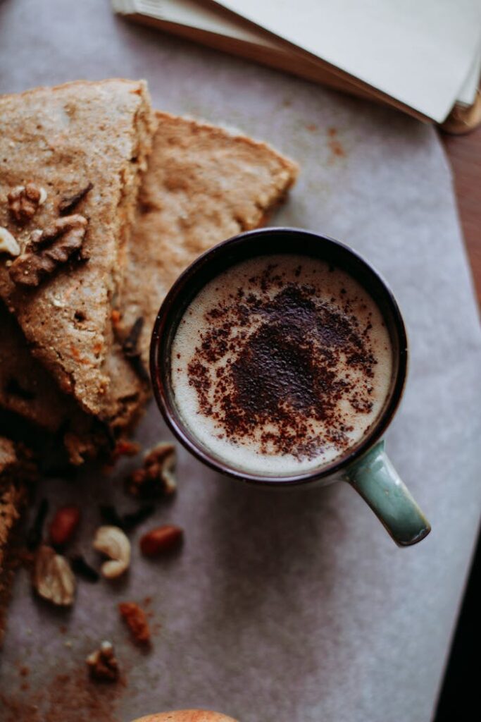 A cup of coffee paired with a slice of homemade carrot cake on parchment paper.