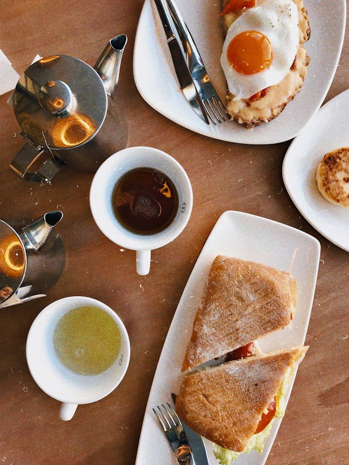 A delightful breakfast scene featuring a sandwich, egg, and tea in a flatlay arrangement.